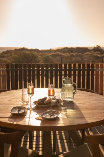 a wooden table with two glasses and a tea kettle at Sea Dunes Luxury Apartments in Moana