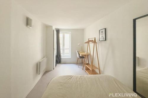 Cette chambre blanche comprend un lit et un bureau. dans l'établissement Flexliving - Onebedroom - Hopital, à Paris