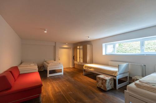 a room with two beds and a red couch at Ferienoase Granula - Bad Ragaz in Bad Ragaz