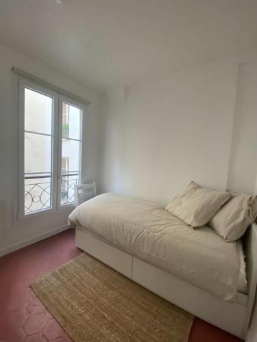 une chambre blanche avec un lit et une fenêtre dans l'établissement Flexliving - Studio - Paradis, à Paris