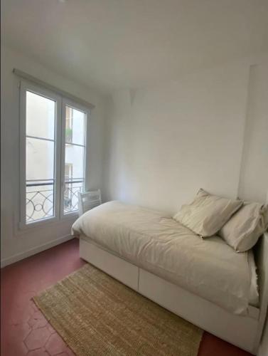 une chambre blanche avec un lit et une fenêtre dans l'établissement Flexliving - Studio - Paradis, à Paris