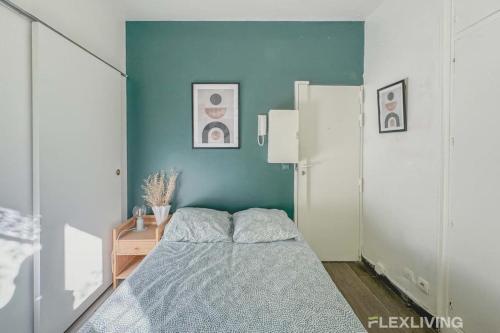 une chambre avec un lit et un mur bleu dans l'établissement Flexliving - Studio - Longchamps, à Paris