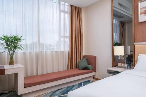 a bedroom with a window with a bed and a window seat at Penguin Airport international hotel & included free shuttle bus in Yinghai