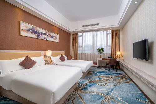 YinghaiPenguin international hotel Baiyun Airport & C-harge shuttle bus for the Canton fair from April 15-May 5的一间有两张床和一台平板电视的酒店房间