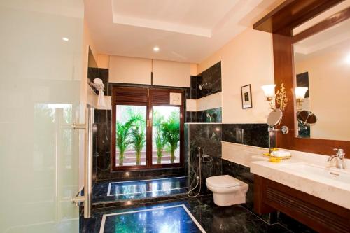 a bathroom with a toilet and a sink and a window at The Kipling Lodge- Nature Kalp in Khilchipur