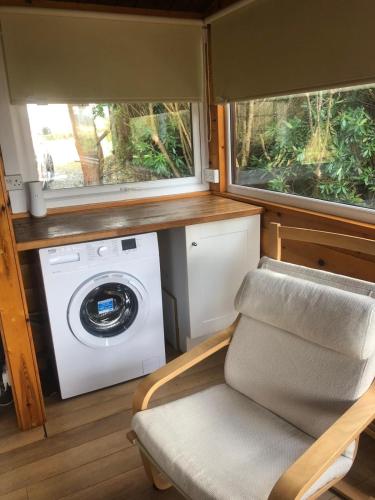 a washing machine and a chair in a tiny house at Misty Mountain Log Cabin - Trawsfynydd in Trawsfynydd