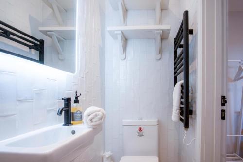 Ty Florence - 3 Bedroom Cottage - Bayview Oxwich في أوكسويتش: حمام أبيض مع حوض ومرحاض