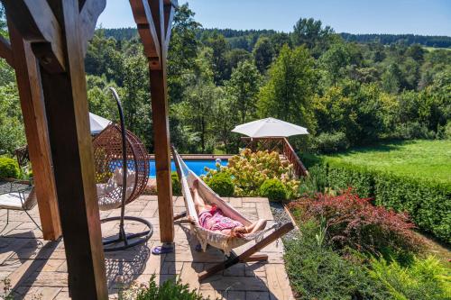 a woman laying in a hammock next to a pool at Tarninowe Wzgórze in Kunkowa