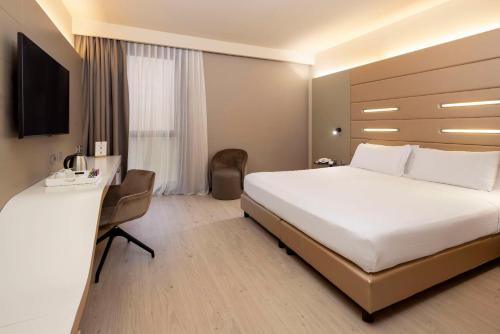 a hotel room with a large bed and a desk at Best Western Plus Tower Hotel Bologna in Bologna