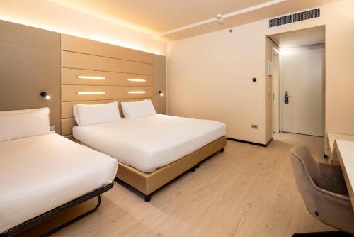 a hotel room with two beds and a desk at Best Western Plus Tower Hotel Bologna in Bologna