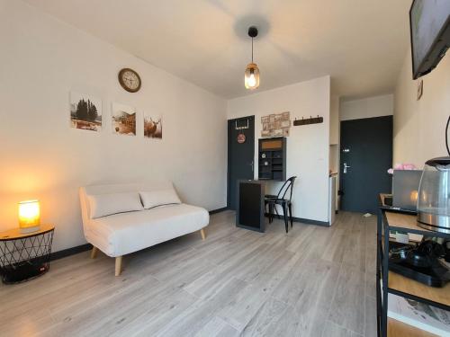 un salon avec un canapé et une horloge au mur dans l'établissement Joli Studio lumineux Centre ville Parking gratuit, à Pau