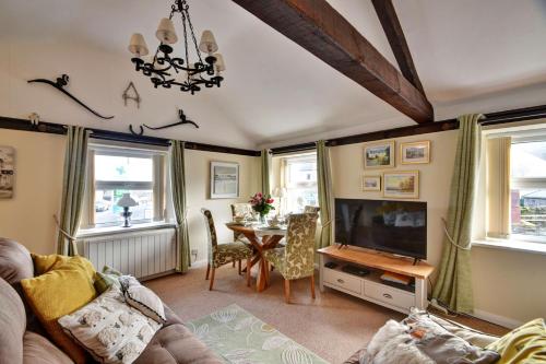 a living room with a television and a table with chairs at Finest Retreats - Dales Barn Top in Hawes