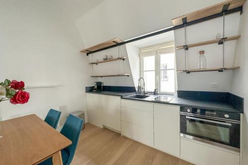 une cuisine avec des placards blancs et une table en bois avec une salle à manger dans l'établissement Flexliving - appartement - Beauregard, à Paris