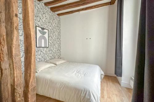 une chambre avec un lit blanc et un mur en pierre dans l'établissement Flexliving - Studio - Linné, à Paris