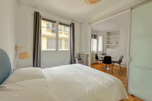 une chambre blanche avec un lit et un bureau dans l'établissement Flexliving - T2 - Médéric, à Paris