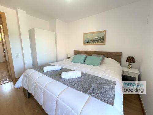 Un dormitorio con una gran cama blanca con dos almohadas. en Paradis Sant Sebastian , climatizado y con piscina, en Salou