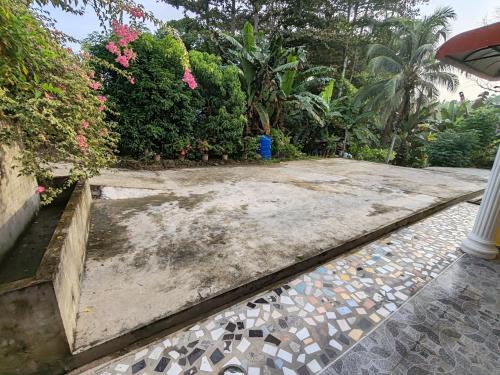 a walkway leading to a garden with flowers and bushes at Sepilok Hideaway Guest House in Sandakan