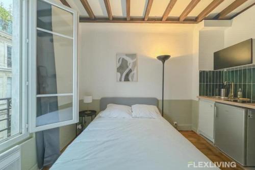 un lit dans une chambre avec une grande fenêtre dans l'établissement Flexliving - Studio - Échiquier, à Paris