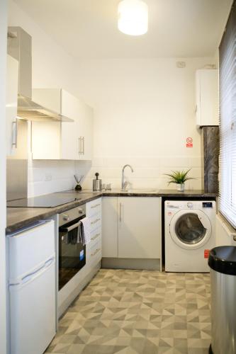 a kitchen with a washing machine and a sink at Aqua Springs, 2 BR, Sofa Bed, Sleeps 6, 1st floor apartment, near Didsbury in Manchester