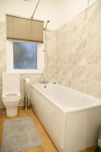 a bathroom with a white tub and a toilet at Aqua Springs, 2 BR, Sofa Bed, Sleeps 6, 1st floor apartment, near Didsbury in Manchester