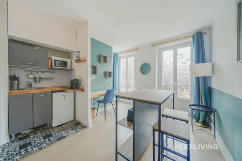 une cuisine avec une table et des chaises dans une pièce dans l'établissement Flexliving - Studio - Dessous des berges -, à Paris