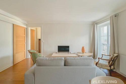 - un salon avec un canapé et une table avec un ordinateur dans l'établissement Flexliving - T2 - Guy de la Brosse, à Paris