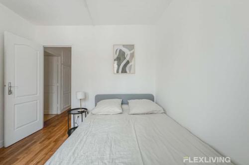 une chambre blanche avec un lit et une table dans l'établissement Flexliving - room - Saint Martin, à Paris