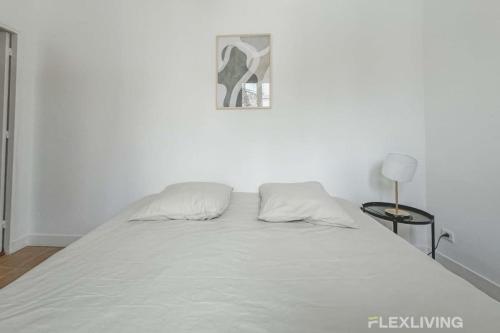 - un lit blanc dans une chambre avec une photo sur le mur dans l'établissement Flexliving - room - Saint Martin, à Paris