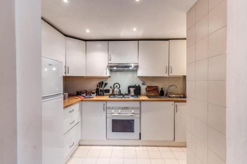 a white kitchen with white cabinets and appliances at Massimo 60 apartment by Roman Dreams in Rome