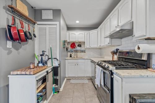 a kitchen with white cabinets and a stove top oven at ALX Cape Cod 3-BR Near Old Town & Mount Vernon in Alexandria