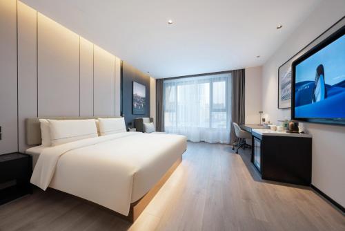 a bedroom with a large white bed and a flat screen tv at Atour Hotel Shijiazhuang Chang'an Guanghua Road in Shijiazhuang