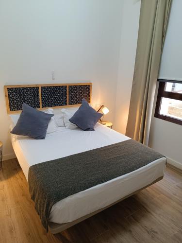 a bedroom with a large bed with blue pillows at Apartamentos AL-QAZERES LUXURY La Concepción in Cáceres