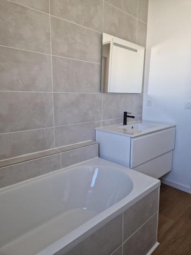 une salle de bain avec une baignoire blanche et un lavabo dans l'établissement Maison climatisée avec piscine, à Sallèles-dʼAude