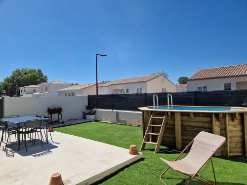 une petite cour arrière avec une table et une piscine dans l'établissement Maison climatisée avec piscine, à Sallèles-dʼAude