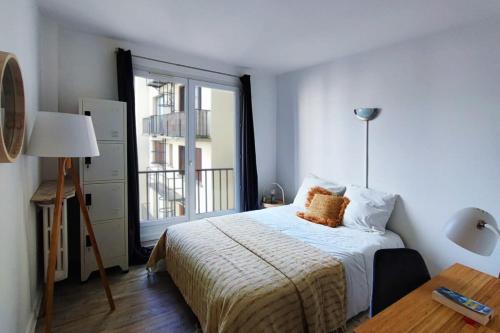 une chambre avec un lit et une grande fenêtre dans l'établissement Flexliving - whole flat - Villon, à Paris