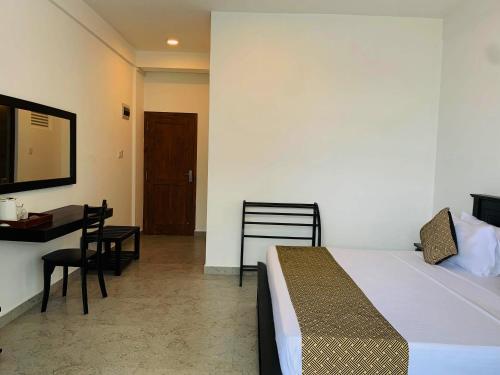 a bedroom with a bed and a table and a desk at Palazzo Beach Hotel in Hikkaduwa