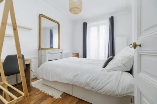une chambre avec un lit, un bureau et un miroir dans l'établissement Flexliving - Charming flat - Caulaincourt, à Paris