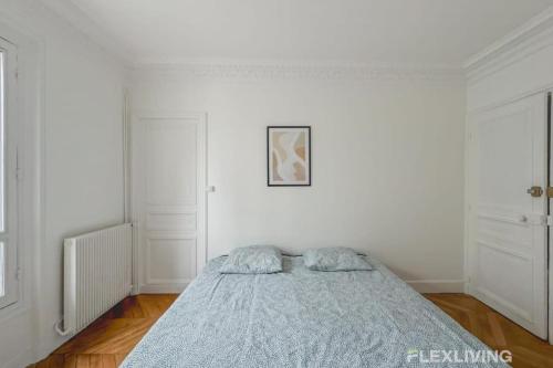 - une chambre blanche avec un lit et une couverture bleue dans l'établissement Flexliving - Charming whole flat R1 - Henri Sellier - Suresnes 92, à Suresnes