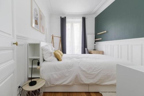 - une chambre avec un lit blanc et un mur bleu dans l'établissement Flexliving - Charming flat - Caulaincourt, à Paris