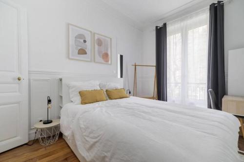 une chambre avec un grand lit blanc avec deux oreillers dans l'établissement Flexliving - Charming flat - Caulaincourt, à Paris