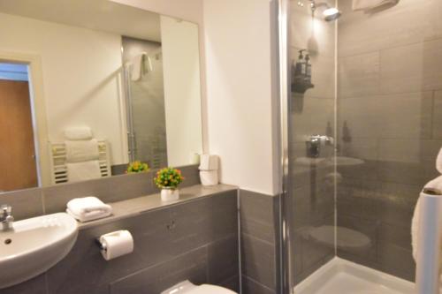 a bathroom with a shower and a sink and a toilet at The Royal Hotel Cardiff in Cardiff