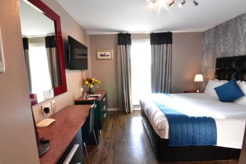 a hotel room with a bed and a mirror at The Royal Hotel Cardiff in Cardiff