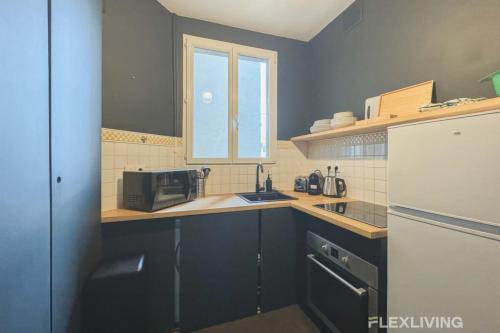 une petite cuisine avec un évier et un réfrigérateur dans l'établissement Flexliving - Whole Flat - Lamarck, à Paris