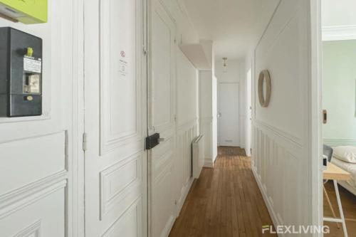 un couloir avec des portes blanches et un plancher en bois dans l'établissement Flexliving - Whole Flat - Lamarck, à Paris