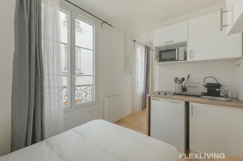 une cuisine blanche avec un évier et un micro-ondes dans l'établissement Flexliving - Studio - Étienne Marcel, à Paris