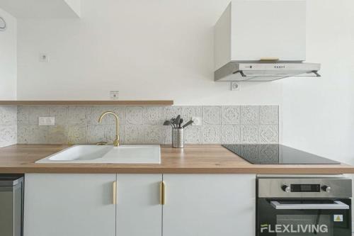 une cuisine blanche avec un évier et une cuisinière dans l'établissement Flexliving - whole apartment - Mouchez, à Paris