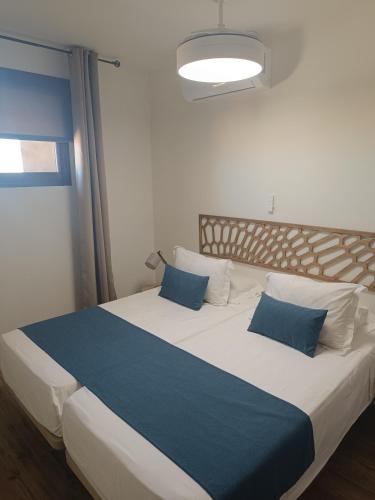 a bedroom with a large bed with blue pillows at Apartamentos AL-QAZERES LUXURY La Concepción in Cáceres
