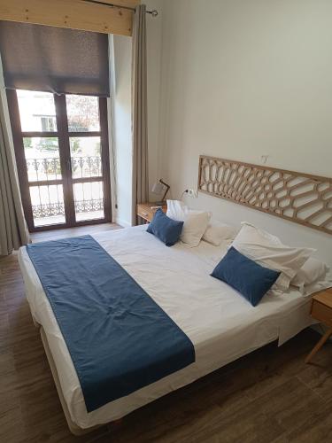 a bedroom with a large bed with blue pillows at Apartamentos AL-QAZERES LUXURY La Concepción in Cáceres