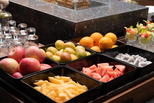 a buffet with apples oranges and other fruits in trays at Atour Hotel Shijiazhuang Chang'an Guanghua Road in Shijiazhuang