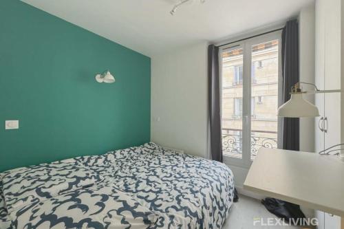 Cet appartement comprend une chambre dotée d'un lit avec un mur bleu et une fenêtre. dans l'établissement Flexliving - whole flat - Bonnet, à Paris